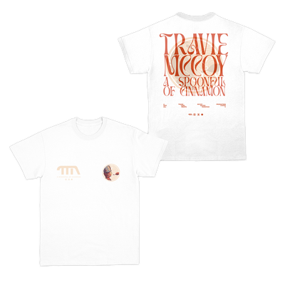 White tshirt with "TM a Spoonful of cinnamon" printed on the front right chest in wavy lettering. A circular logo illustration of a boy with a bucket on his head being fed a spoonful of cinnamon is on the left chest. Both of these are printed on the full back, the name overlaid on top of the illustration.